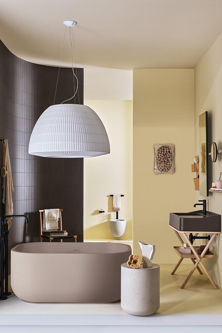 Nell’immagine, Siwa di Ceramica CIELO, disegnato da Andrea Parisio e Giuseppe Pezzano, il mobile con lavabo in ceramica nella finitura Fango della gamma cromatica “Terre di Cielo”  abbinato a un vassoio e una struttura in legno finitura Rovere Naturale. A parete specchiera Siwa nella versione rettangolare, con struttura in legno in finitura Rovere Naturale e Sacca portaoggetti in cuoio naturale. Completa la composizione la vasca Dafne in LivingTec nella finitura Arenaria della gamma cromatica “Terre di Ciel