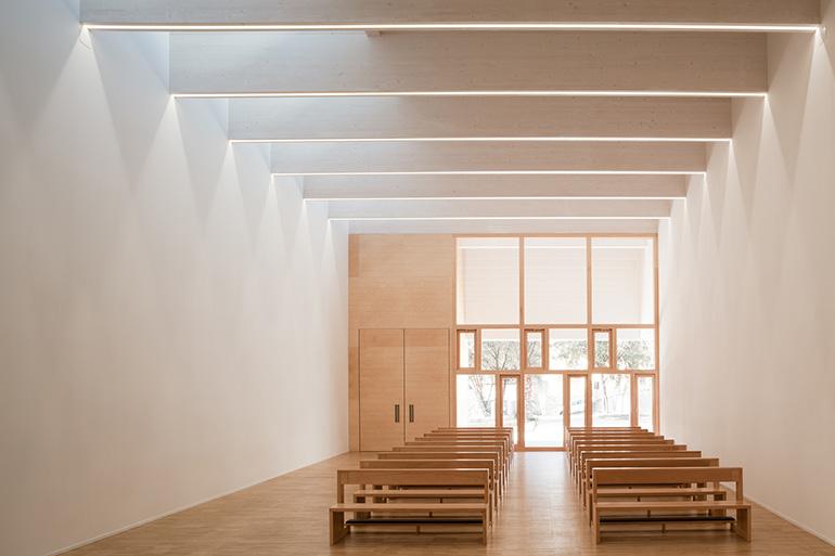 La giuria riconosce che il Complesso parrocchiale di Santa Chiara “si colloca nell’area centrale del piccolo abitato di Sini, nella Sardegna interna, con rigore formale e consapevolezza contestuale, cogliendo l’occasione per ricucire una serie di elementi spaziali, espressivi e relazionali del tessuto centrale. Interpretando elementi tipici dell’edilizia spontanea locale e di un’architettura sobria della koiné mediterranea, il progetto agisce in un contesto difficile per rinnovare i nessi di senso con le co