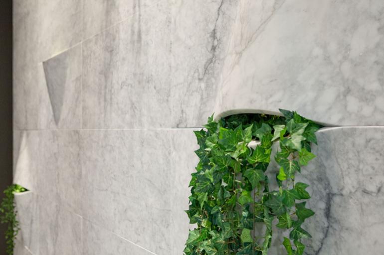 Bianco Carrara Superficie &ldquo;Lips&rdquo; -  La parete in Bianco Carrara presenta una finitura satinata Alcuni pannelli sono stati lavorati e sagomati per permettere l&rsquo;inserimento di elementi decorativi: si possono cos&igrave; creare progetti di lighting design, garden decor con piante verdi o fiori, oppure attrezzare la parate con elementi funzionali come diffusori di essenze o umidificatori.